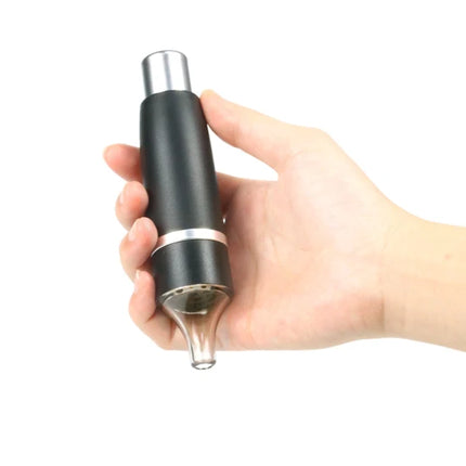 Manual press grinder held in hand; black handle with clear grinding chamber and silver spout