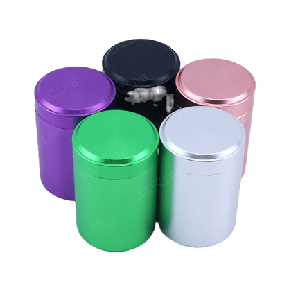 Set of metal storage jars with flat screw-top lids in green, purple, blue, pink, and silver.