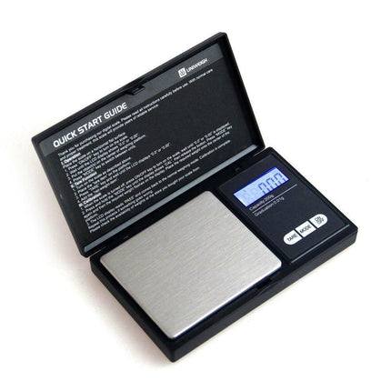 Digital pocket scale with opened quick-start cover and blue LCD display in black case.