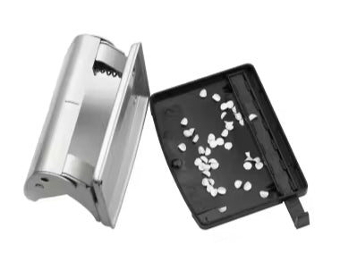 Metal two-hole punch with open silver and black lid and cutouts on tray.