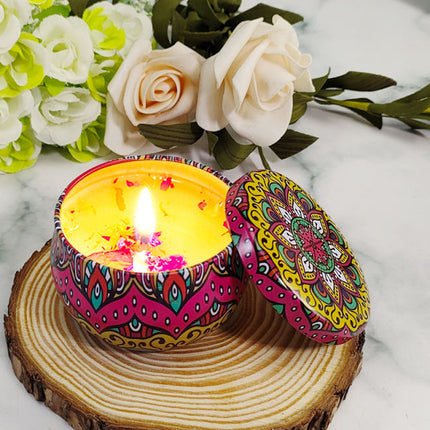 Lit soy votive candle in colorful patterned tin, yellow wax, lid open