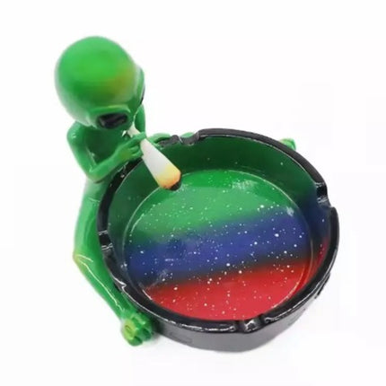 Alien ashtray with green figurine beside dark galaxy bowl