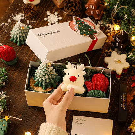 Reindeer-shaped Christmas candle in open 3-piece gift box with pine and red candles