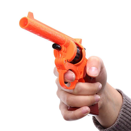 Orange cowboy cap gun toy revolver in a hand, plastic revolver with trigger