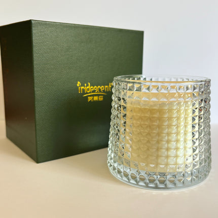 Faceted glass soy candle jar, lit, with green gift box behind