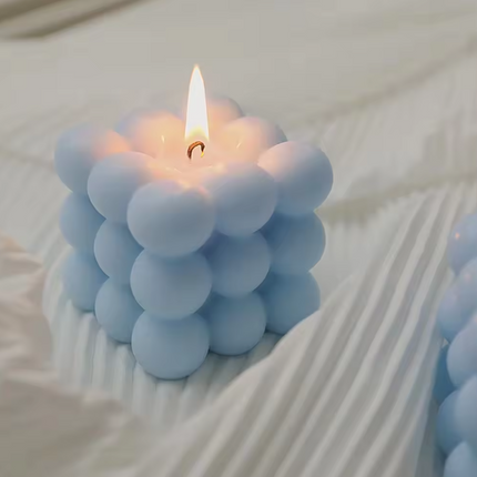 Blue bubble cube scented candle with a flame, close-up view of the top