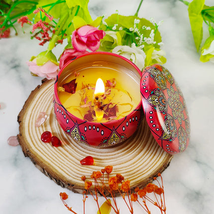 Soy scented candle in red patterned votive tin, lid open, flame burning.