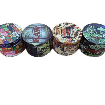 Metal herb grinder with several printed lids stacked, showing black interior chambers