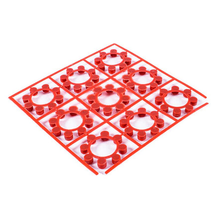 Red shot ring caps with white center inserts on a molded plastic grid sheet