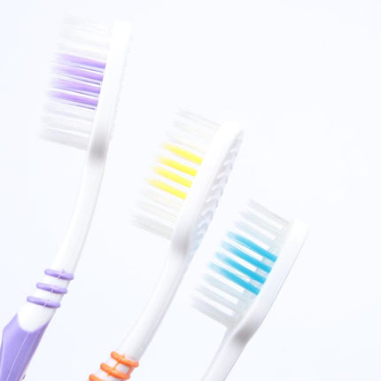Curved toothbrushes with soft bristles, showing purple, yellow, and blue brush heads