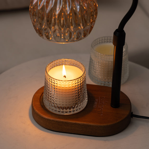 Lit soy candle in faceted glass on wooden base with black holder