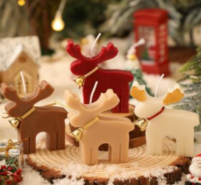 Set of Christmas reindeer-shaped candles with lit flames on a winter village base