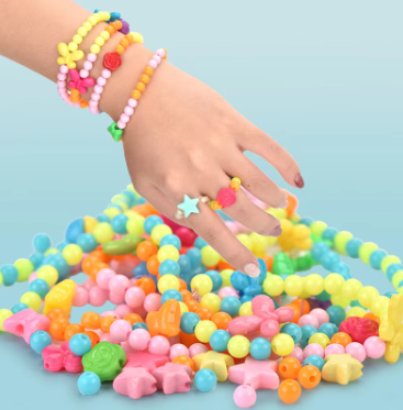 Child wearing colorful bead bracelets and star charm bracelet stack