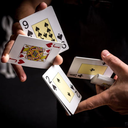 Deck of playing cards held in hands, showing 9 and 2 suit cards