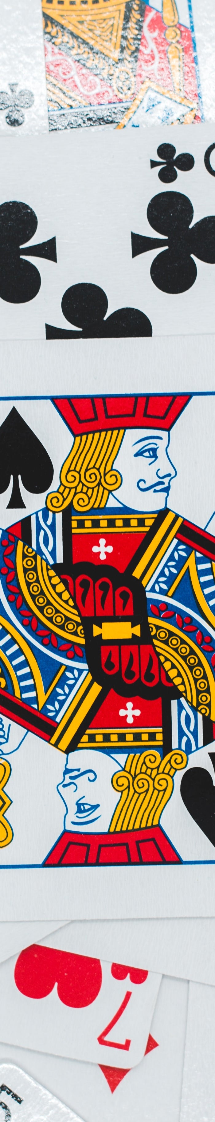 Playing cards spread out showing black clubs and red hearts with a king playing card