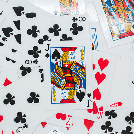 Playing cards spread out showing black clubs and red hearts with a king playing card