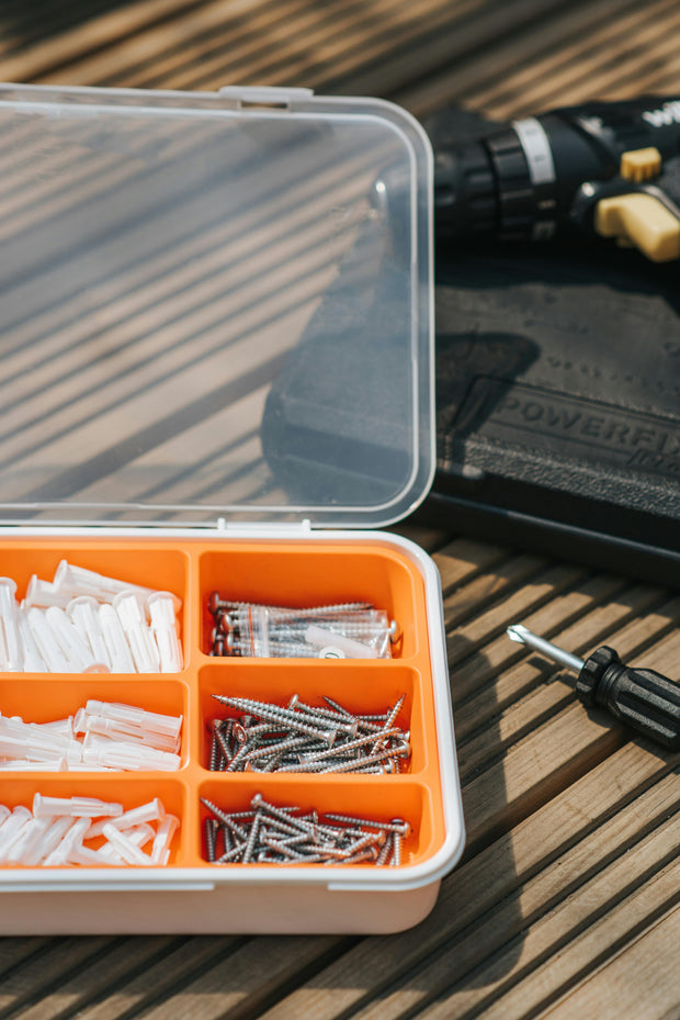 Organized hardware kit with screws, wall plugs, and tools on wooden surface for DIY projects