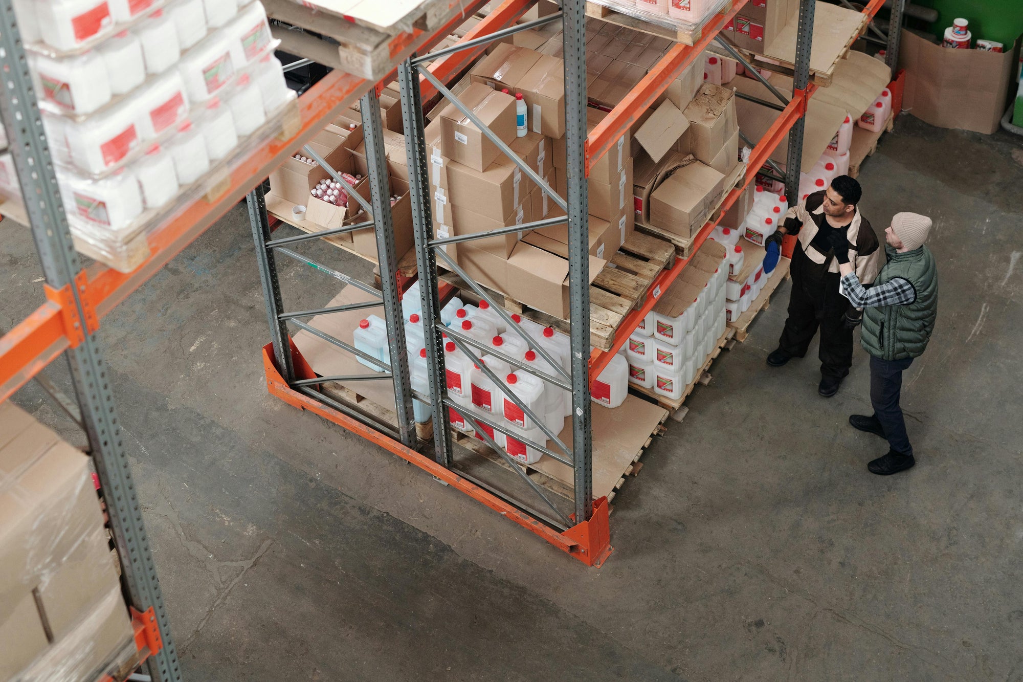 Warehouse staff discussing wholesale products among stocked shelves and pallets for retail supply